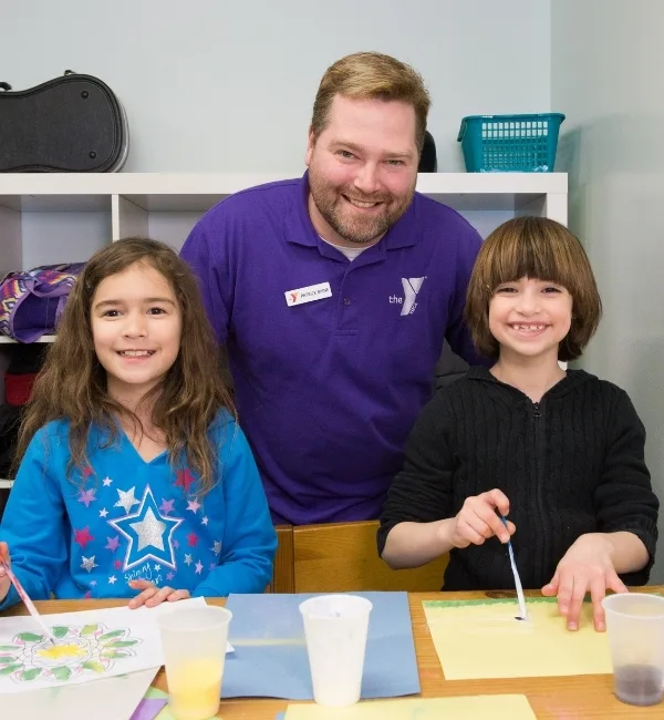Teaching staff member helping children paint