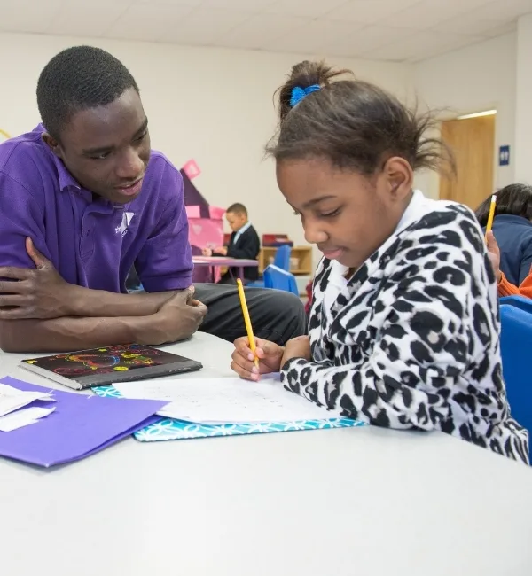 Teaching staff member helping a child write