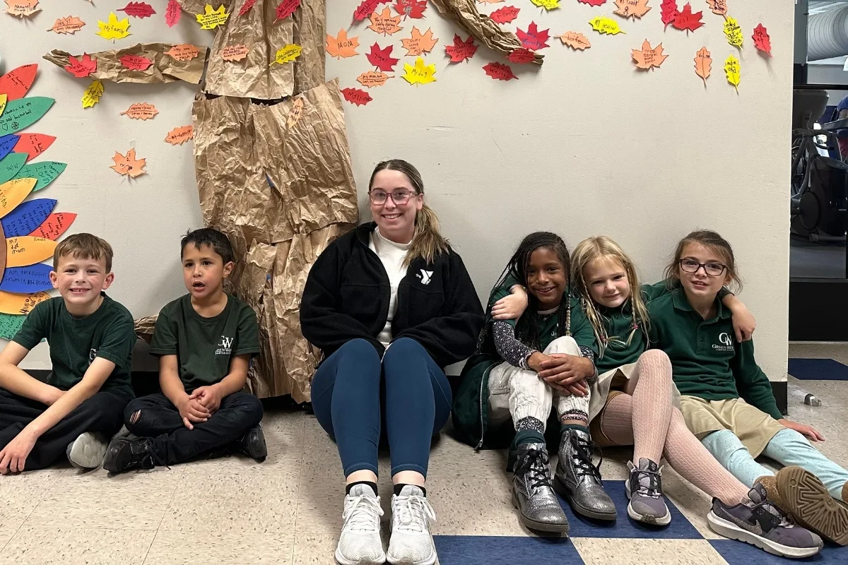 Teaching staff member sitting with a group of children in a school