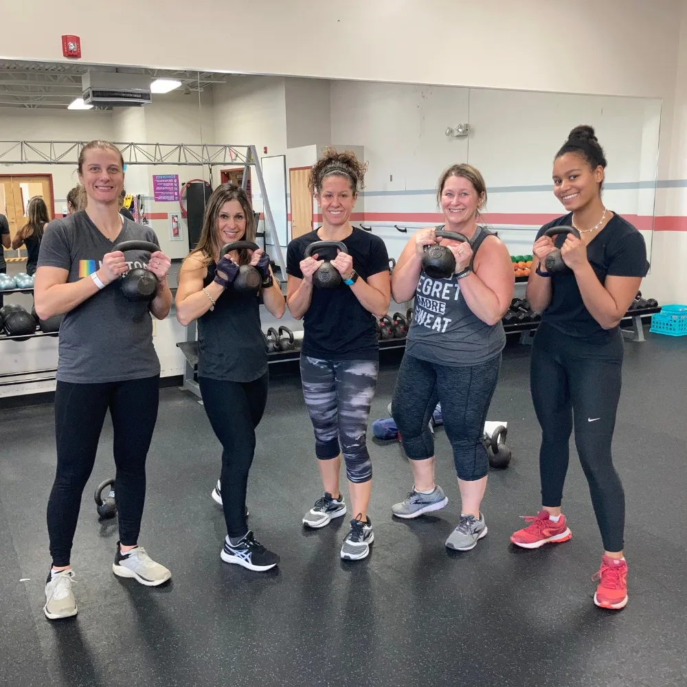 Small group exercise class holding kettlebells inside studio