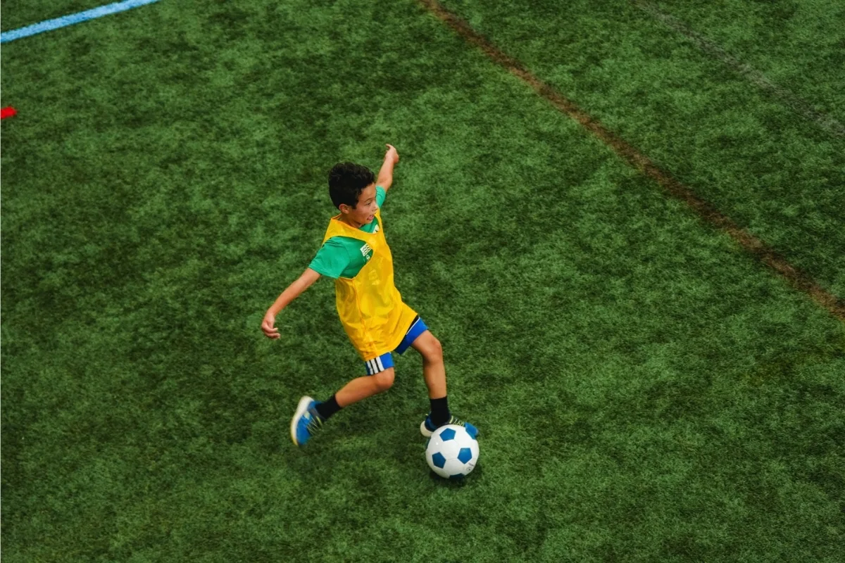 Youth kicking a soccer ball on turf
