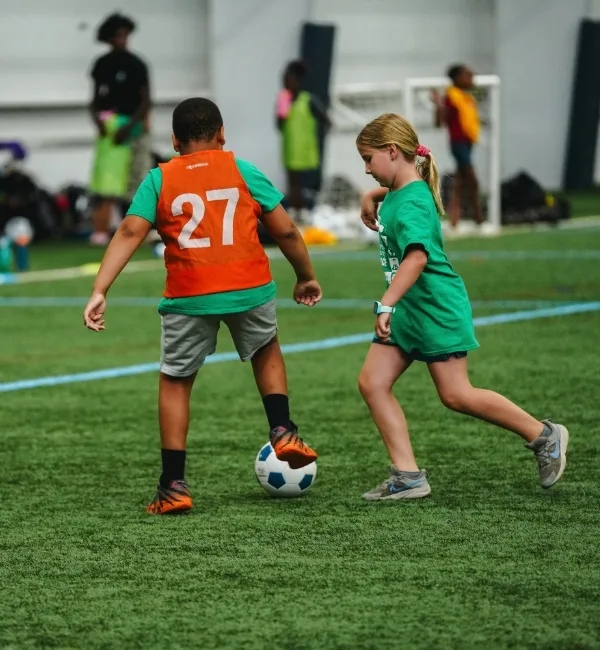 Youth practicing soccer on turf at indoor sports complex