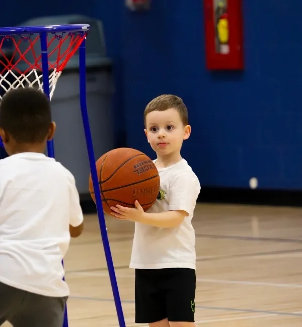 Child holding basketball on indoor basketball court