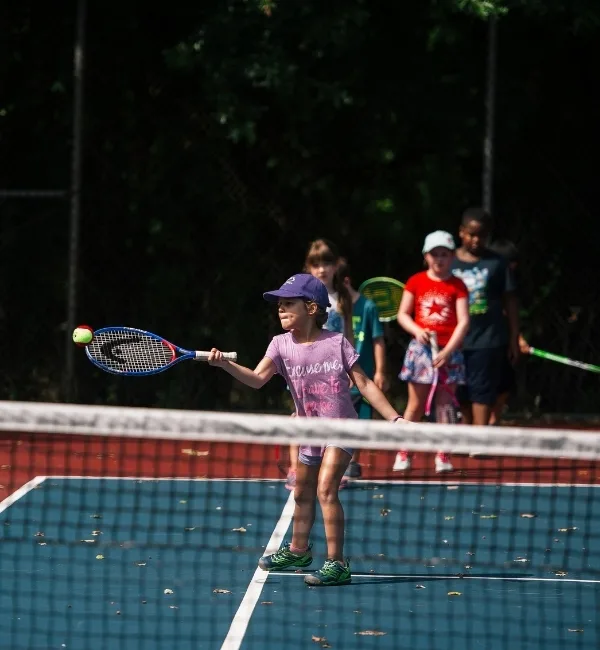 Youth practicing tennis on outdoor tennis court