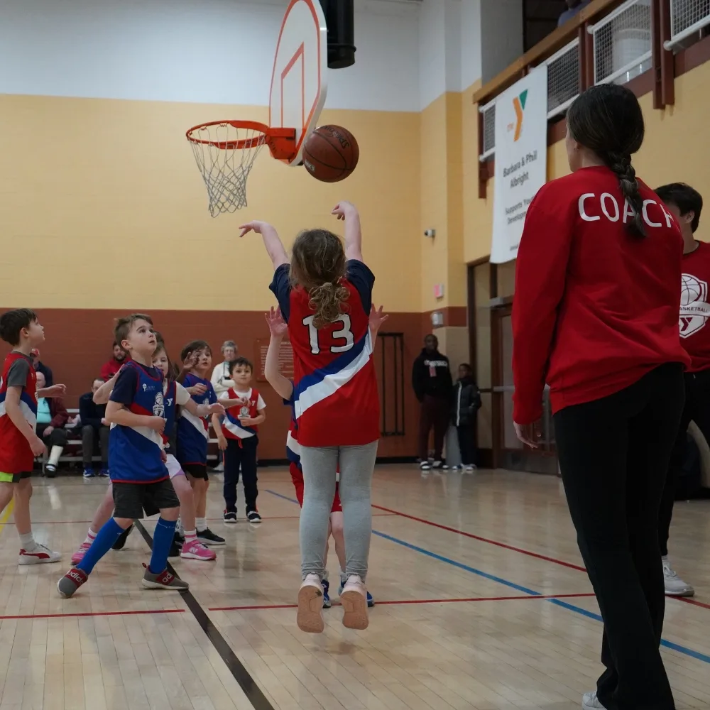 Youth basketball team member shooting a basketball on an indoor basketball court