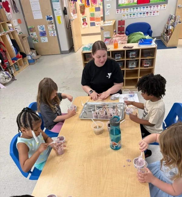 Group of children and Pre-K staff member making food in classroom