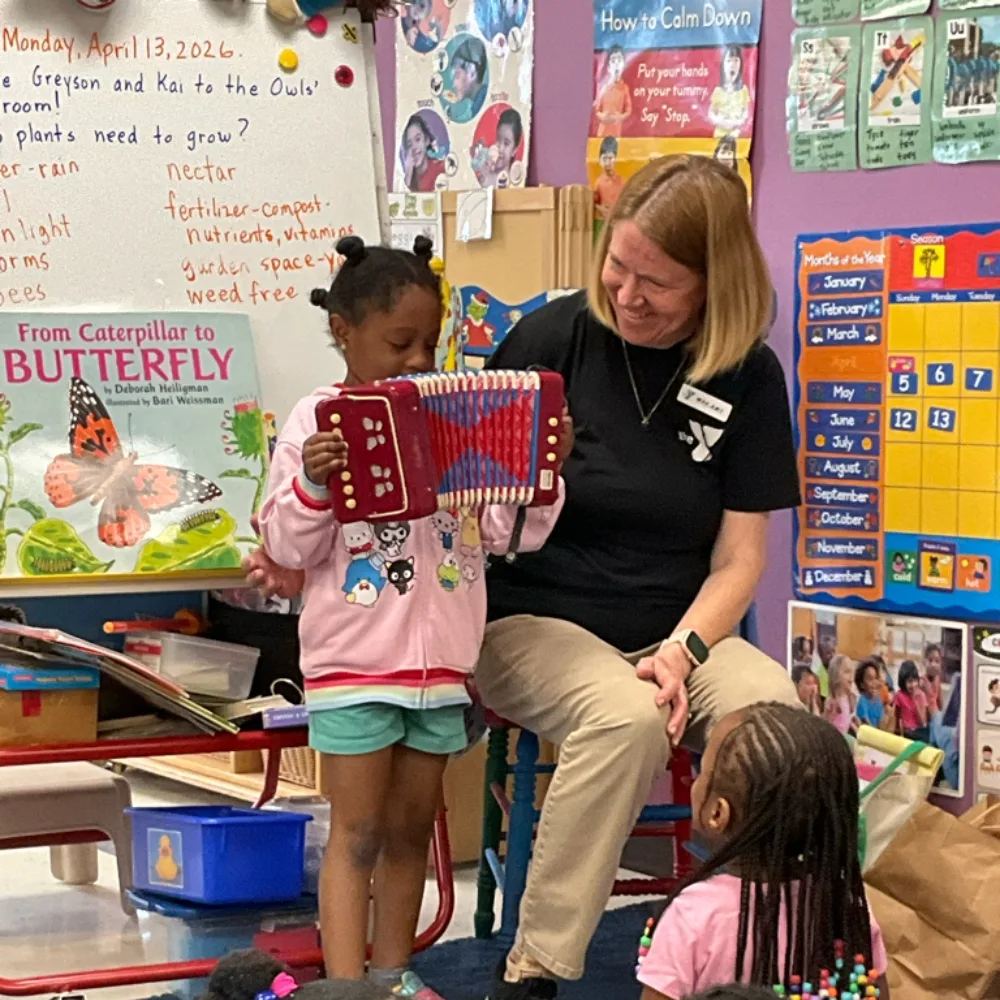 Pre-K staff member with child playing a toy instrument