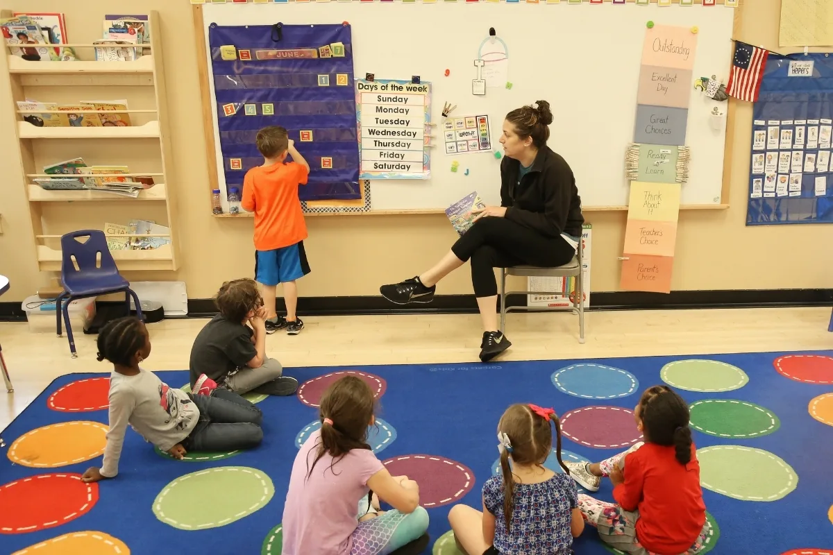 Kindergarten staff member teaching a group of children in a classroom