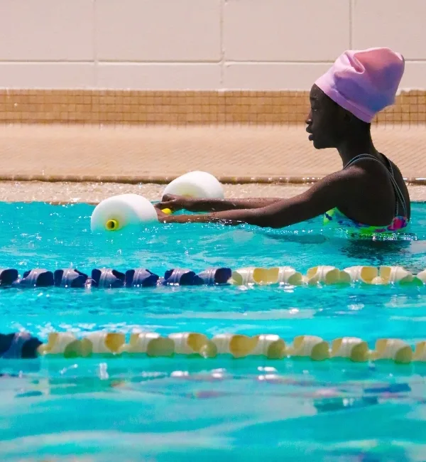 Youth learning to swim using swim equipment in indoor pool