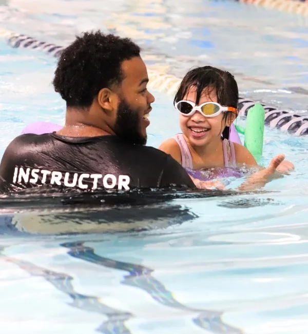 Swim instructor teaching a child how to swim in indoor pool