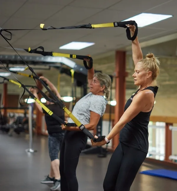 Small group exercise class using TRX equipment inside fitness center