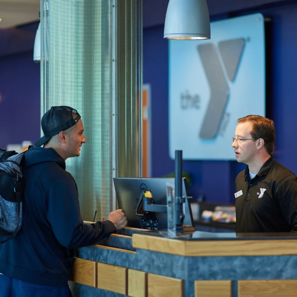 Y staff member helping a member at the front desk