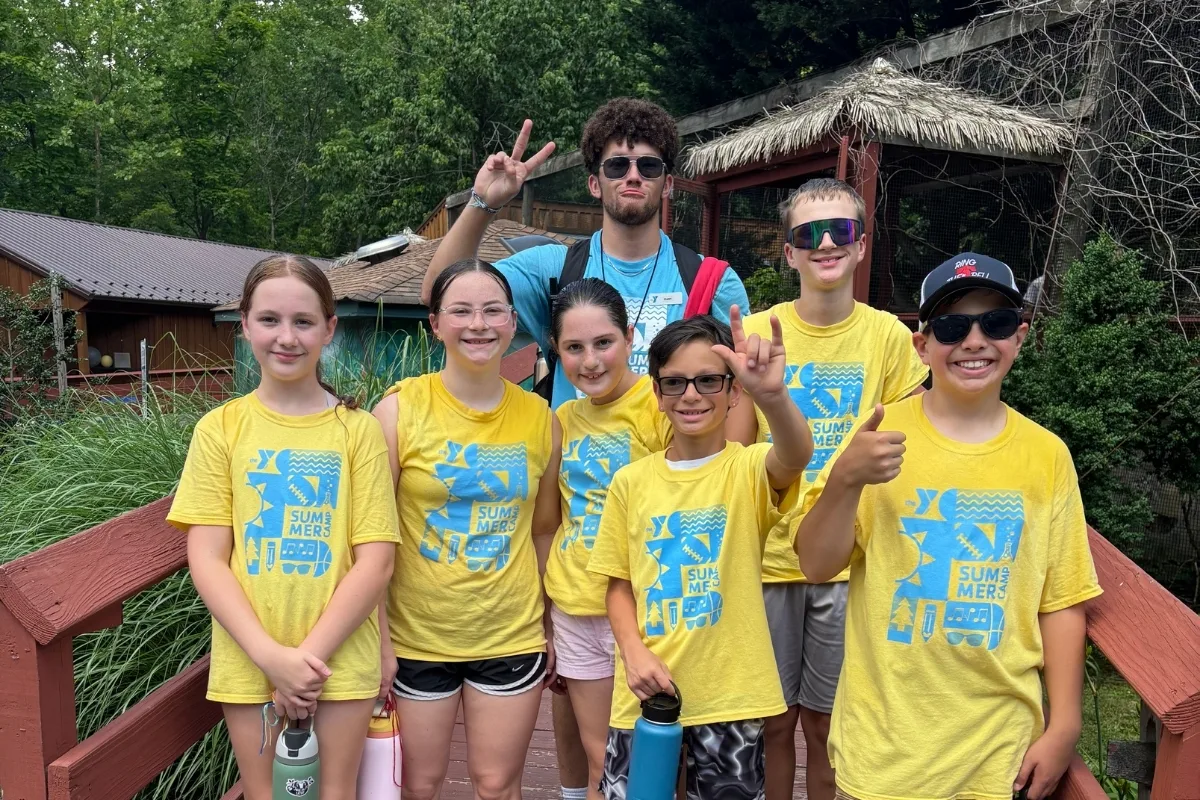 Campers and camp counselor posing on a bridge outdoors at Upper Perkiomen Valley Y's summer camp